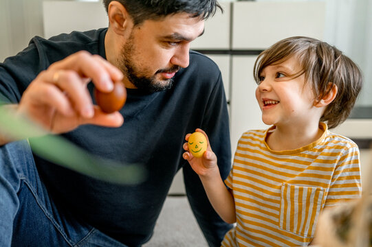 Father and son holding decorated eggs for Easter at home