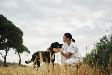 Happy woman stroking dog in field