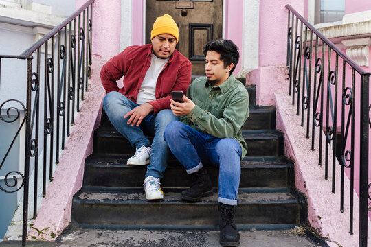 Man with brother using smart phone at steps