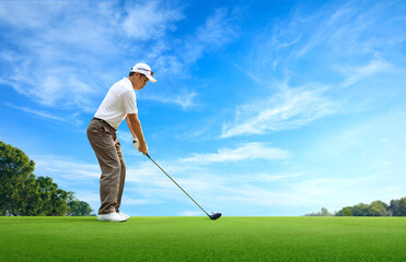 Golf approach shot with driver on golfing ground with blue sky background.