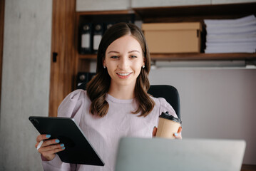 Fototapeta premium Beautiful business woman typing laptop and tablet Placed at the table at the office