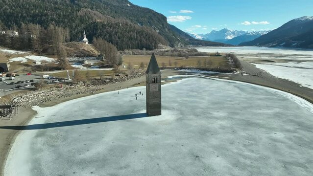 Drone dolley shot to the Sunken church of Graun at the reschen lake with alps in the background.