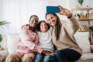 Woman taking selfie with family sitting on sofa at home