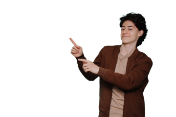 Handsome caucasian guy in casual pointing by index fingers at copy space against transparent background. Brunet Italian boy smiles looks at camera. Discount, sale, promo.