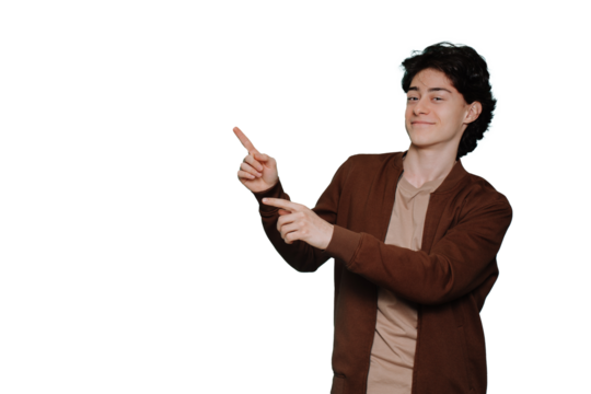 Handsome caucasian guy in casual pointing by index fingers at copy space against transparent background. Brunet Italian boy smiles looks at camera. Discount, sale, promo.