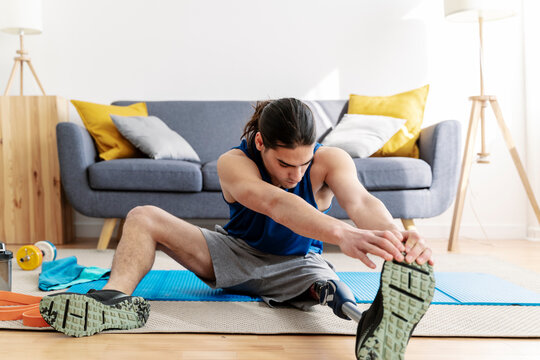 Young man with disability warming up before exercise at home