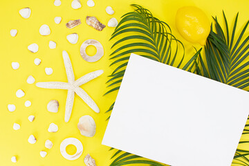 White starfish, shells with palm leaves and paper for text on side on yellow background. Flat lay. Travel, vacation, summer. Copy space