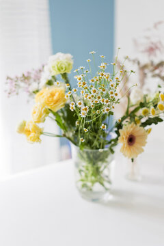 Yellow and white flowers in glass vase on table