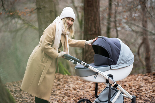 Smiling woman with baby stroller in forest
