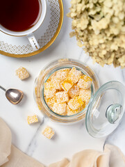 Pleasant tea drinking: a cup of freshly brewed tea and a sweet treat on a side table. Small bars of Turkish delight marmalade.