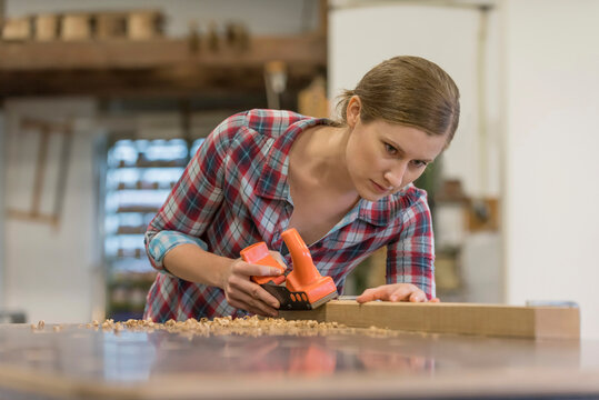 Dedicated trainee shaving wood in workshop