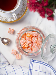 Pleasant tea drinking: a cup of freshly brewed tea and a sweet treat on a side table. Small bars of Turkish delight marmalade.