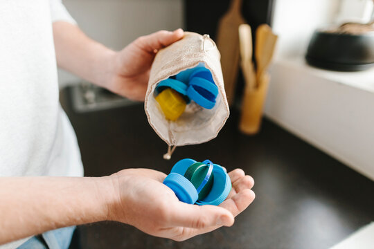 Hands of man with bottle caps at home
