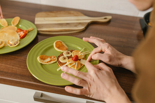Man preparing bunny face with pancakes on plate at home