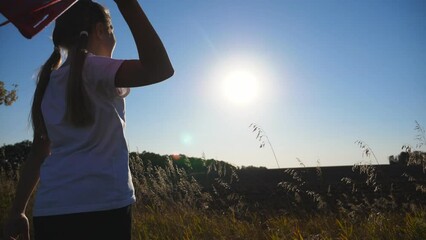Small female child playing with airplane at grass lawn. Happy little girl launching toy plane against the sunlight at background. Carefree kid having fun at nature. Concept of childhood dream. Slow mo