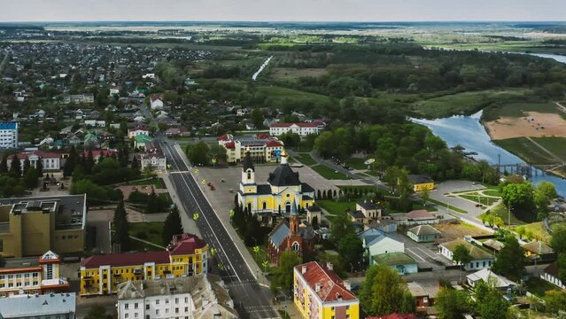 Rechytsa, Belarus. Aerial View Of Residential Houses, River Dnieper And Holy Assumption Cathedral In Sunny Summer Day. Top View. Drone View. Bird's Eye View. Drone Hyper lapse.