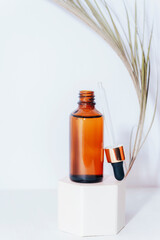 Brown serum bottle with pipette on a podium. Natural skin care cosmetics concept. Closeup