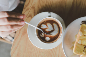 Hot cappuccino, vintage style coffee powder and coffee beans with green leaves On a black background
