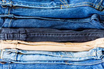 Close up stacked of blue, brown and black Jeans on white background. jeans pattern fashion  concept.