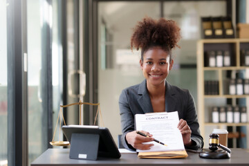 Beautiful young woman lawyer sitting at table and holding contract document in the office.