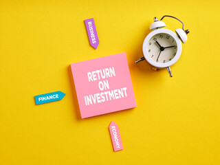 The word return on investment on pink note paper. Business investment concept.