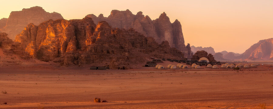 Camp site tents at Wadi Rum Desert, Jordan and red rocks sunset banner landscape
