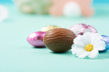 Easter Basket, Sweet Colorful Chocolate Easter Eggs, Daisy Flowers on Pastel Blue Mint Background.