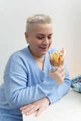 Portrait of adult white woman with short hair holding Greek pita souvlaki in hand. Cheerful Ukrainian female enjoying the lunch in fast food restaurant