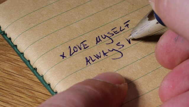 Writing self love note on notebook paper, macro close up view