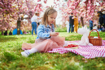 preschooler girl in tutu skirt enjoying nice spring day in cherry blossom garden