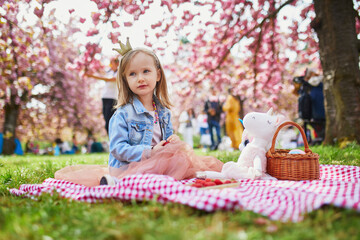 preschooler girl in tutu skirt enjoying nice spring day in cherry blossom garden