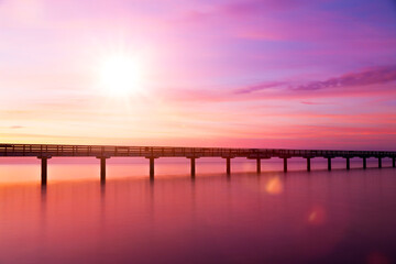 Brücke über Wasser bei Sonnenaufgang in violetter Farbstimmung