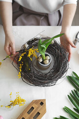 Easter wreath diy with woman hands, flowers on table, handicraft
