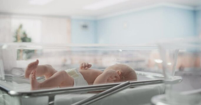 Portrait of a Young Newborn Baby Lying in a Bassinet in a Maternity Ward After Birth. Cute Neonate Child Calling for Mother, Feeling Energetic and Sleepless. Childbirth and Medical Clinic Concept