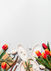 easter floral mockup with bunny plate, cutlery, tulips and gifts, confetti on white grey...