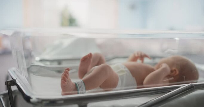 Nurse Putting Identification Hospital Name Tag on a Newborn Caucasian Child. Healthy Infant Baby Lying in a Maternity Clinic, Waiting for Mother to Recover After Childbirth. Close Up Footage of Hands