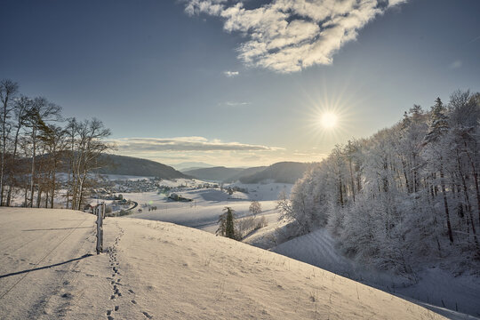 Winterlandschaft im aargauischen Fricktal. Sonnenaufgang &uuml;ber dem Wald mit Blick auf das Dorf M&ouml;hntal.