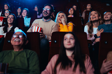 Joyful couple watching funny movie in theater.