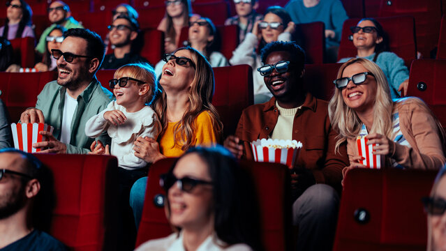 Joyful people watching 3D movie in cinema.