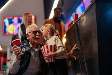 Fototapeta na wymiar Grandfather and granddaughter bonding at movies.
