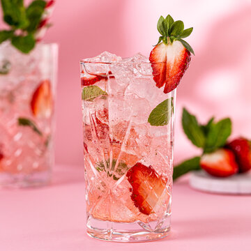 Fresh limonate with crushed ice, strawberry and mint on pinkbackground. Summer cold drink concept with copy space