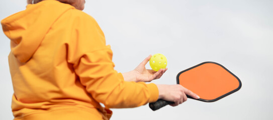 back view pickleball game woman player, hands over blue sky hitting pickleball yellow ball with...