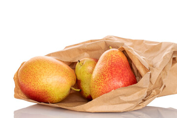 Three ripe yellow-red pears in a paper bag, close-up, on a white background.