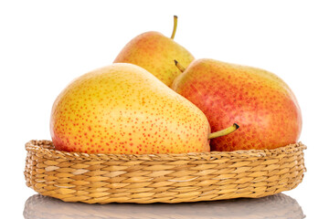 Three ripe yellow-red pears on a straw plate, close-up, on a white background.