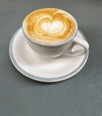 Top view of espresso cup with heart-shaped foam on gray background 