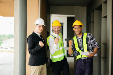 Architect caucasian man working with colleagues mixed race in the construction site. Architecture engineering on big project. Building in construction process interior. look at camera.