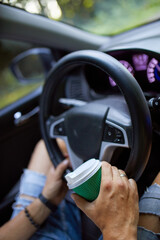 Joyful man driving car while drinking coffee on trip