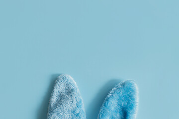 Happy Easter! Blue bunny ears flat lay on blue background. Stylish festive template with space for text. Greeting card or banner. Easter hunt, minimal composition