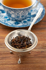 Antique old fashion silver tea strainer and stand with wet tea leaves close up