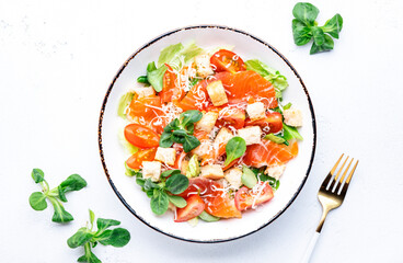 Caesar salad with salted salmon, iceberg and lamb lettuce, croutons, parmesan cheese with caesar dressing. White table background, top view